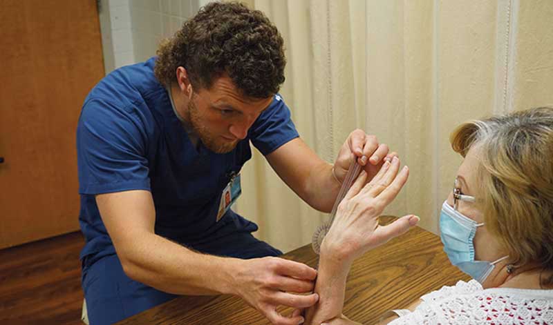 Pershing Health System occupational therapy team member assists a seated patient with hand and arm movement exercises to improve mobility and coordination.