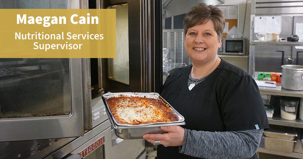Meagan Cain, Nutritional Services Supervisor, holding a tray of food in a kitchen setting.