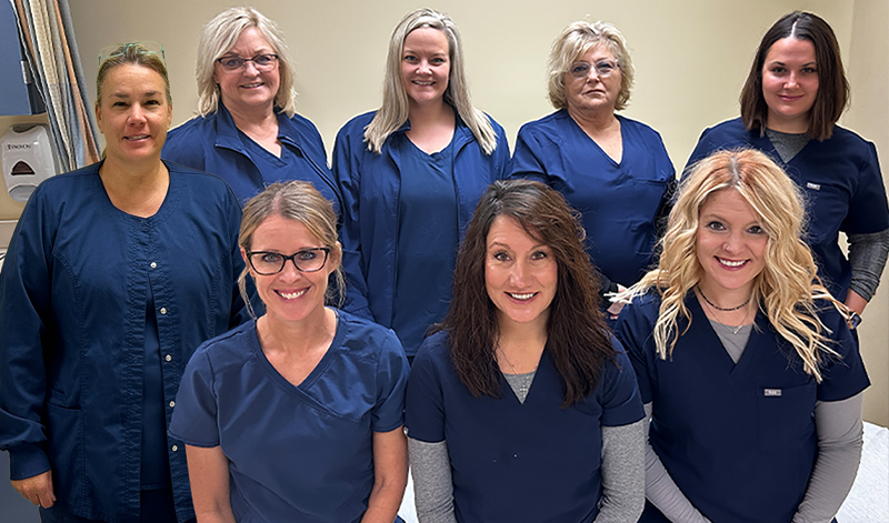 Eight Pre-Op nurses smiling together in blue scrubs at Pershing Health System.