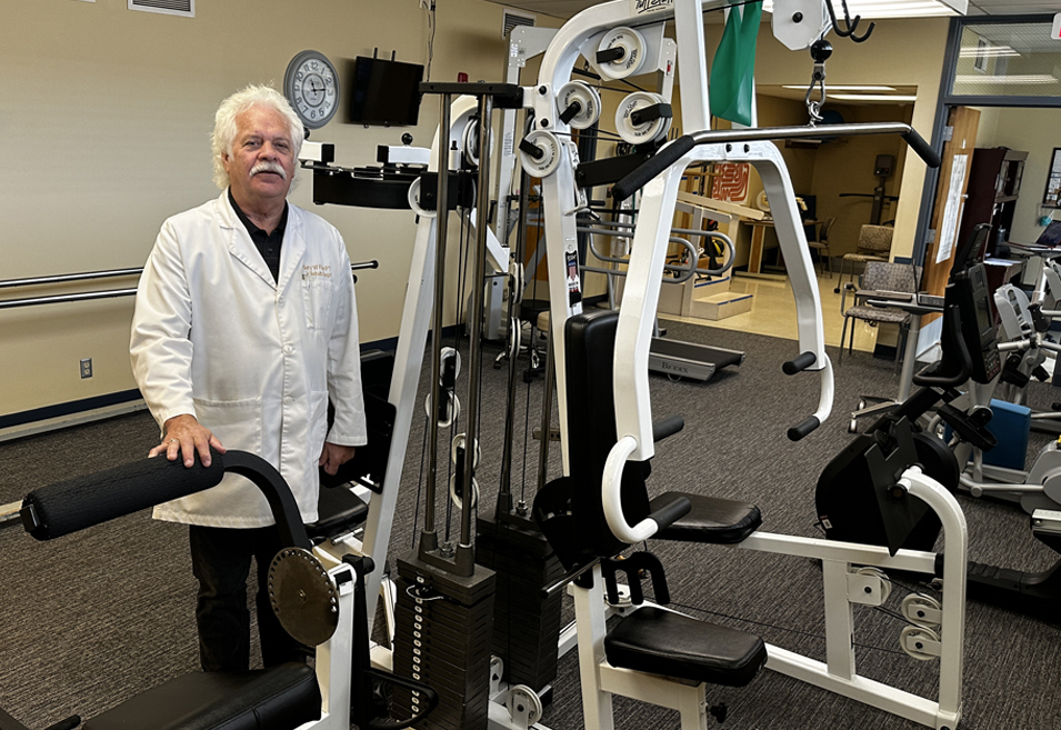 Pershing Health System Physical Therapy team member standing beside strength-training and rehabilitation equipment in the therapy department at Pershing Memorial Hospital