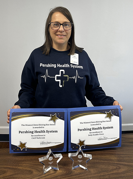 Amy Menconi, Rural Health Clinic Quality Care Specialist at Pershing Health System, proudly displays awards recently presented to PHS Rural Clinics by their Accountable Care Organization (ACO).
