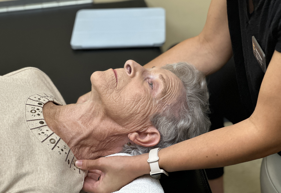 Pershing Health System physical therapy team member gently supports an older patient's neck during a hands-on therapy session.